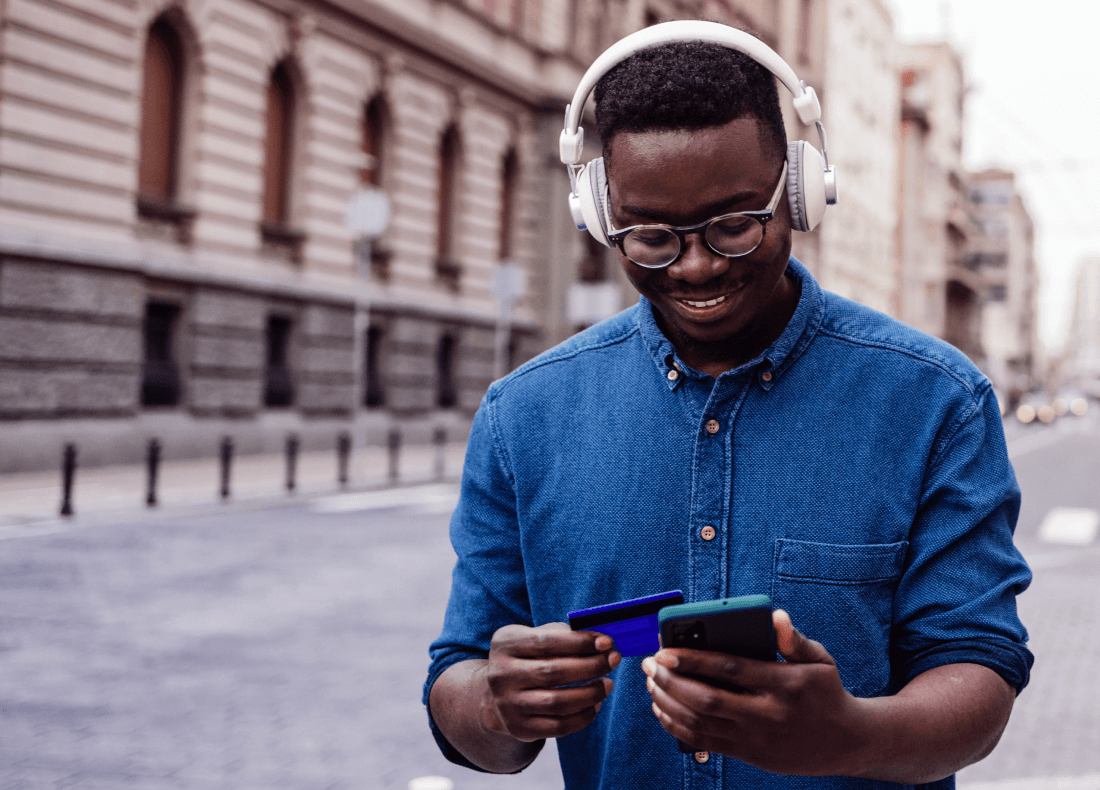 men wearing headphones and glass on the street and looking at his smartphone