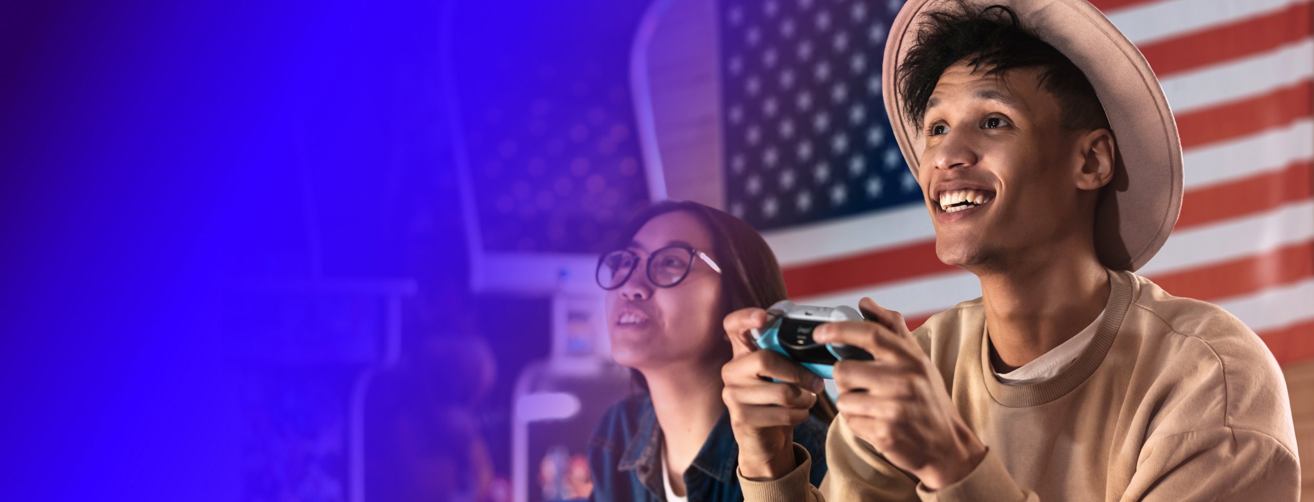 Two teenagers playing a video game with the USA flag behind.