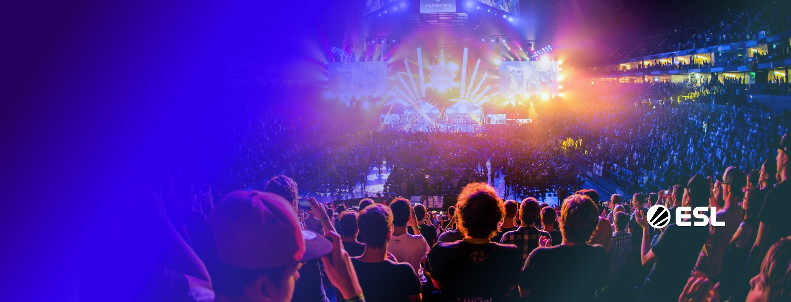 A large crowd of people watching an esports match in an arena