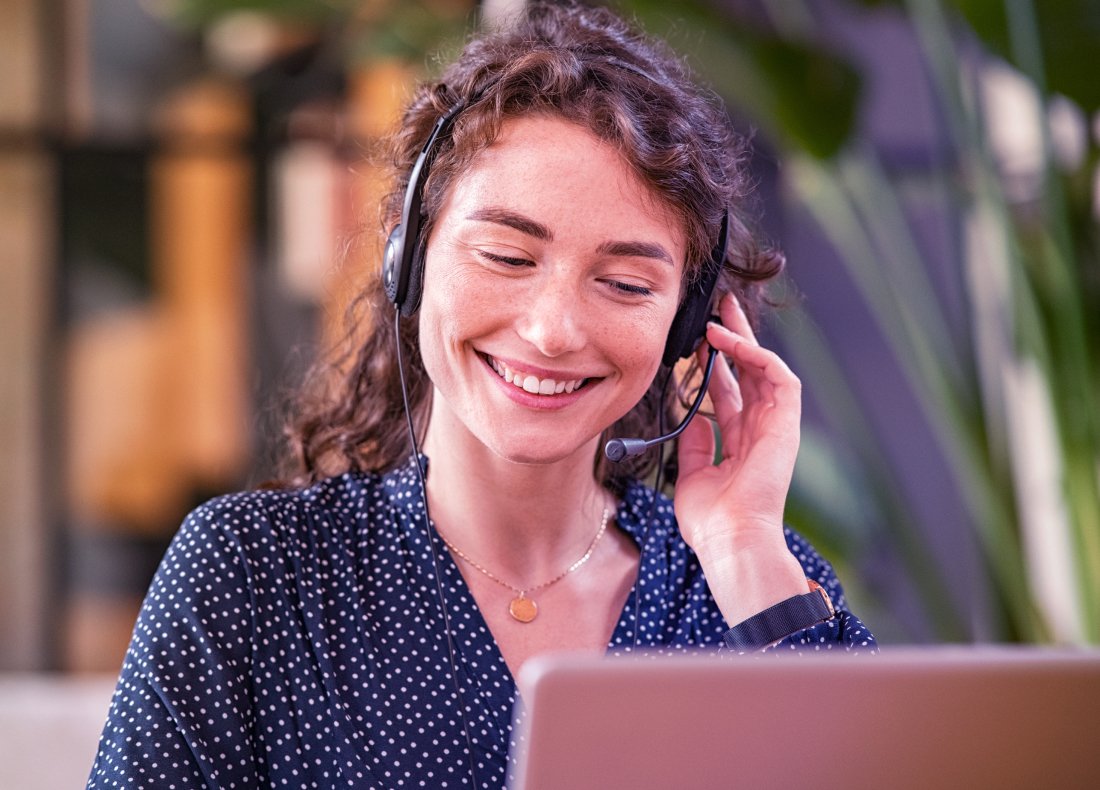 a young female professional with a headset smiling while on an online call