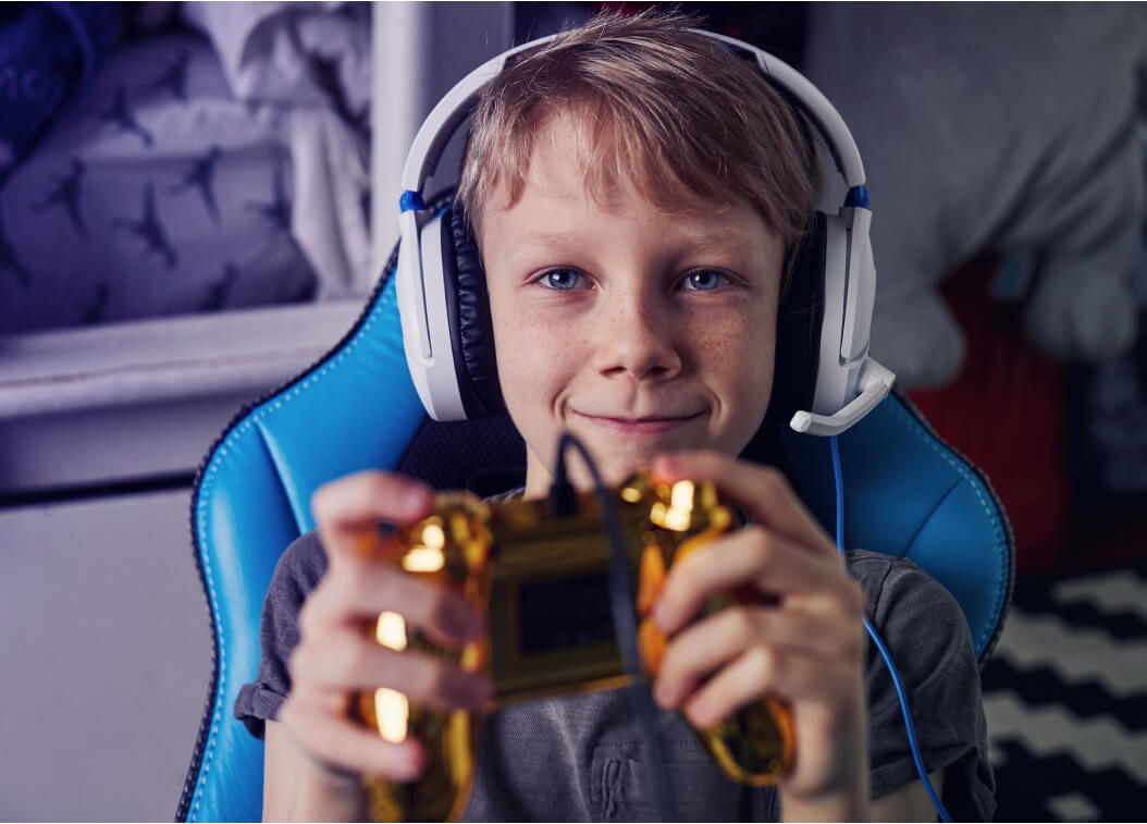 Child with headphones playing video games and smiling