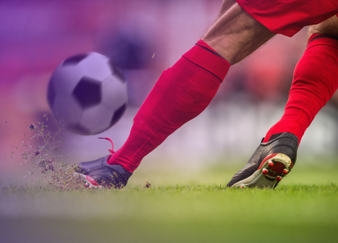 close up of a soccer player in red boots receiving a ball.