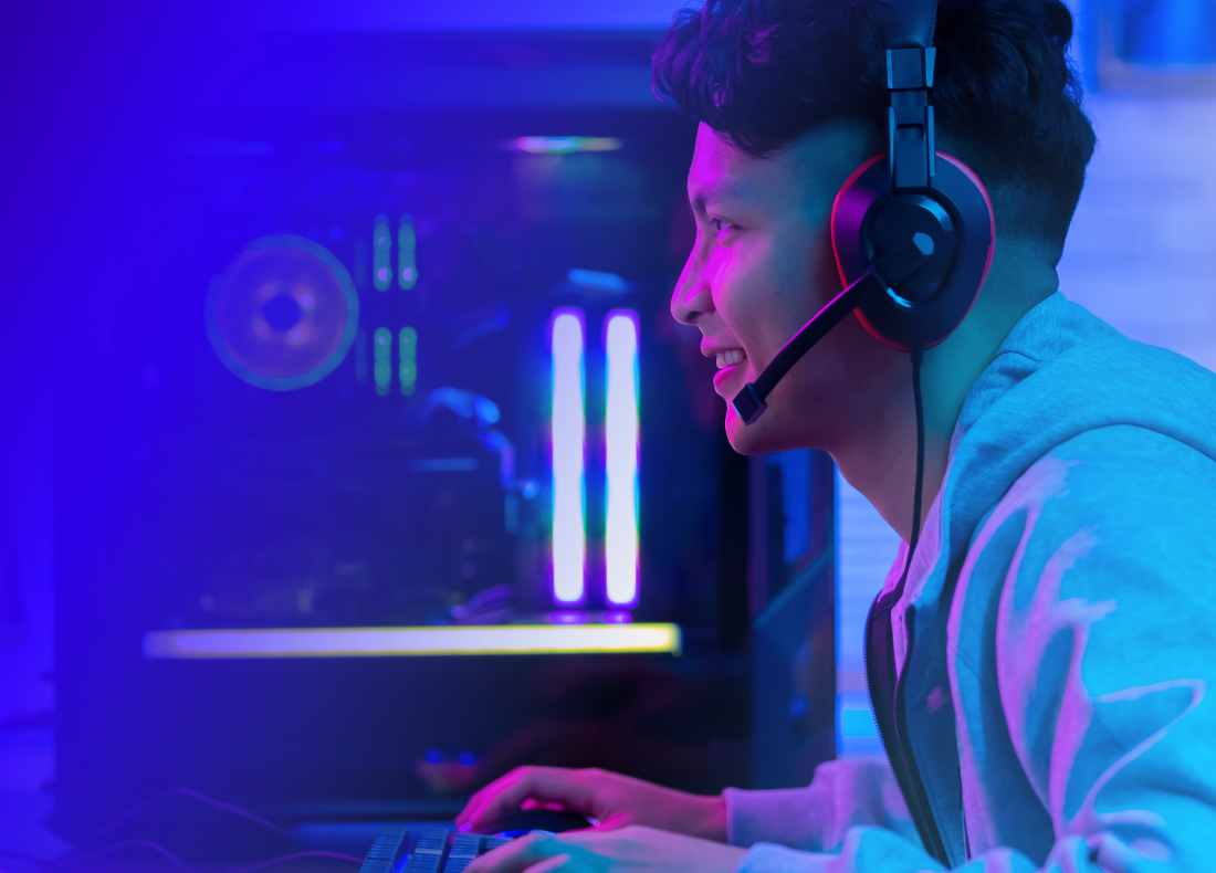 a boy wearing headphones playing a video game at his gaming computer