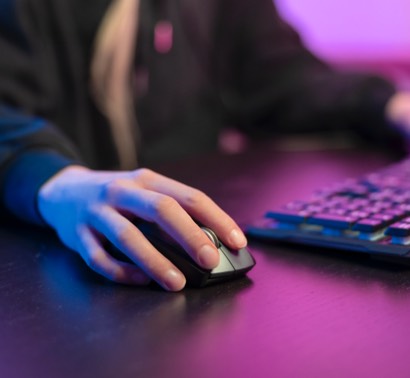pessoa sentada à mesa com computador e rato na mão