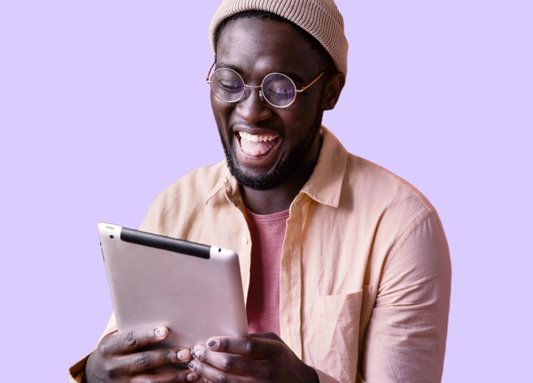 A young man holding an iPad with a wide smile on his face.