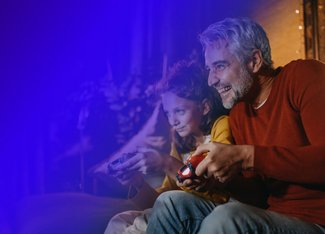 middle aged father and daughter playing video games together